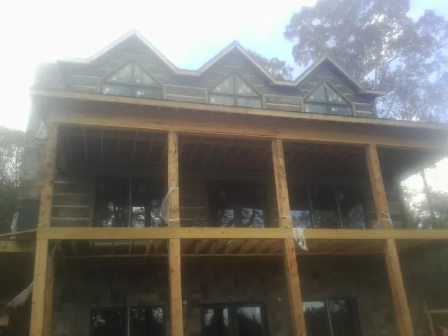 Dormers and porch framing on a large log home under construction — Roof Coating work by our crew in Biloxi