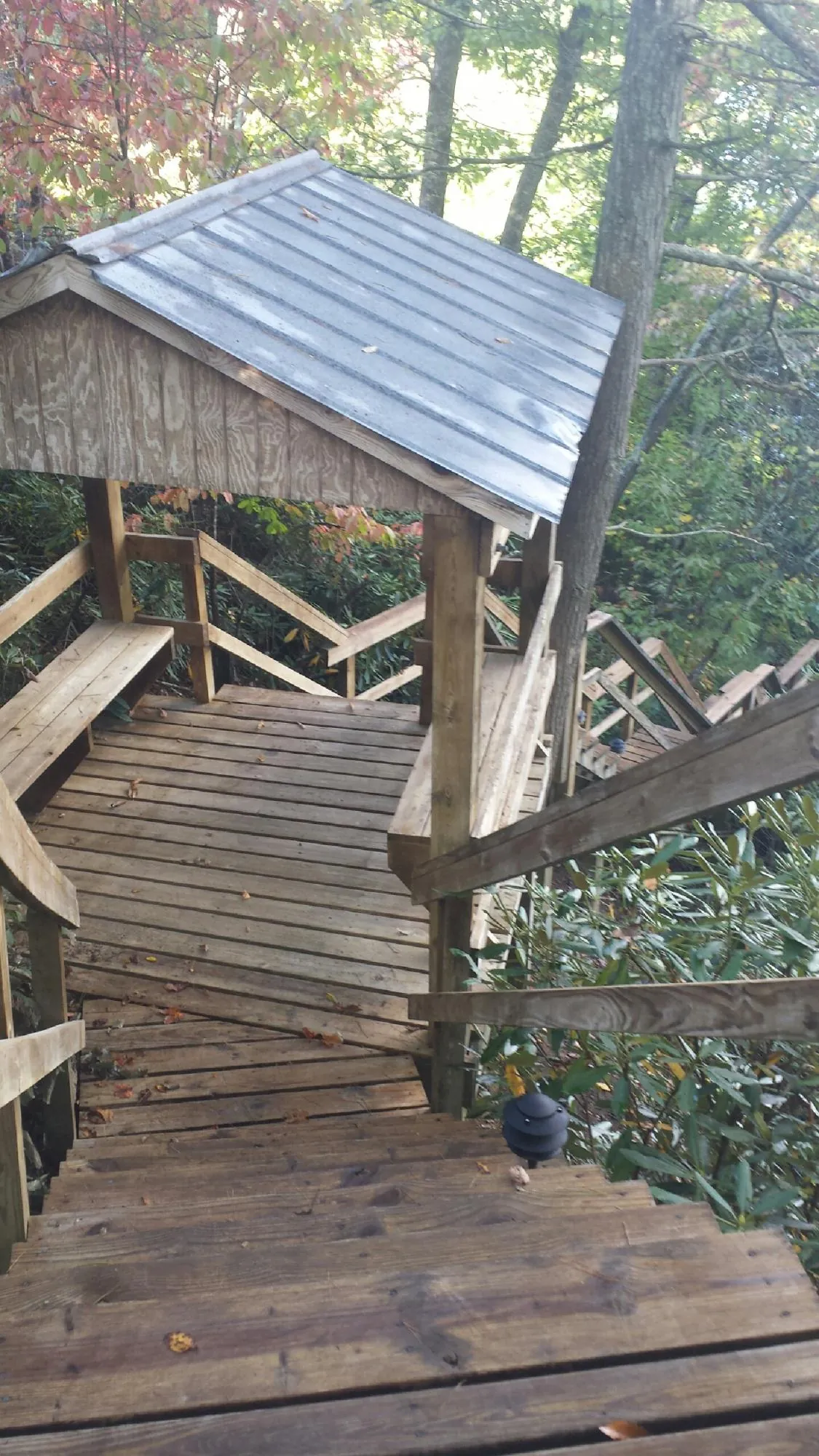 Metal roofed shelter over wooden steps on a wooded walkway — Skylight Repair & Installation work by our crew in Biloxi